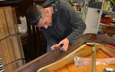 Jo, the polisher mending a dent on the side of a Chappell
Grand piano
